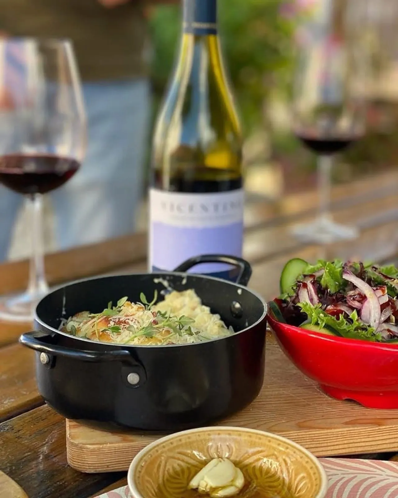 Dinner table set with a home-cooked meal, Alentejo wine and fresh salad in the courtyard