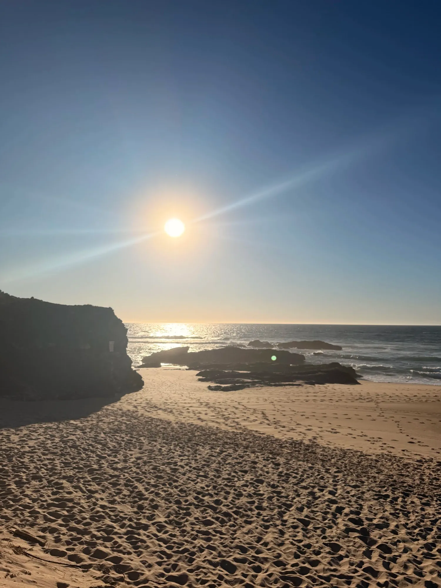 Golden sunset casting long shadows across a rocky Alentejo beach