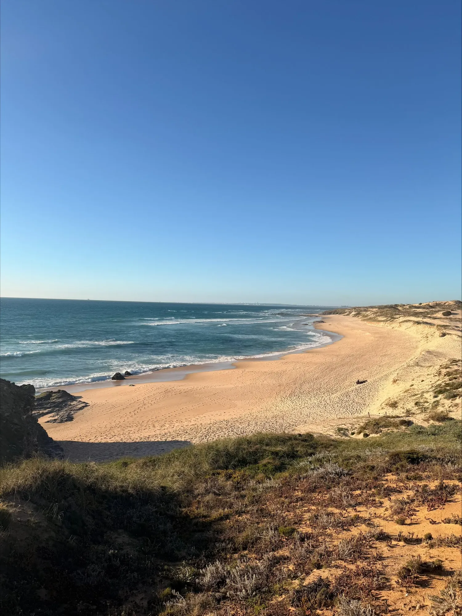 Wild Alentejo coastline with golden sand stretching toward turquoise Atlantic waters