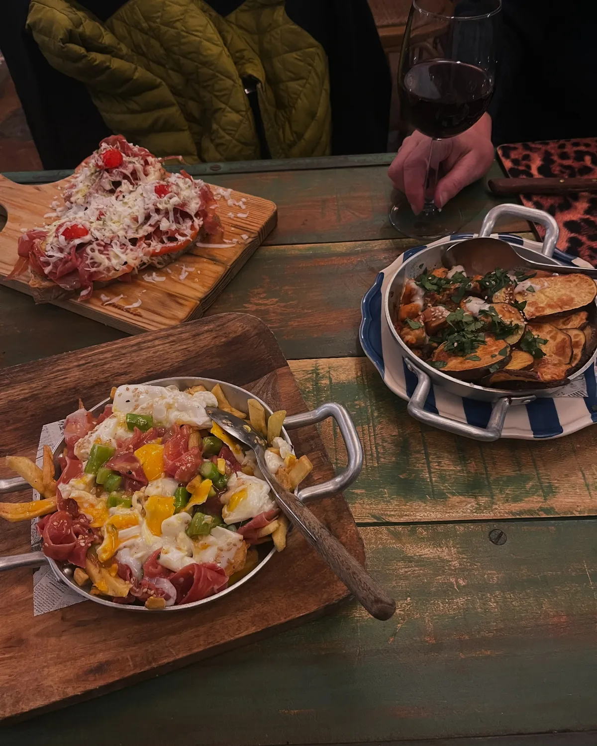 Rustic Portuguese tapas served in copper pans on a painted wooden table with red wine