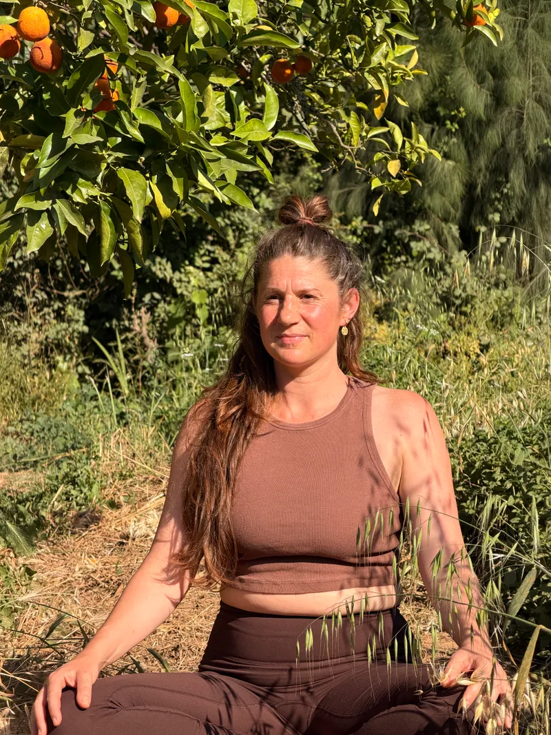Myrna in soft evening light among tall grasses and orange trees at Casa Alma, dressed for her yoga practice