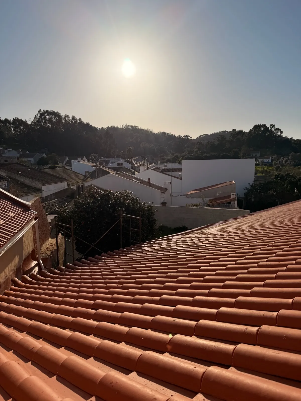 View across terracotta rooftops of São Luís at sunset with hills in the distance